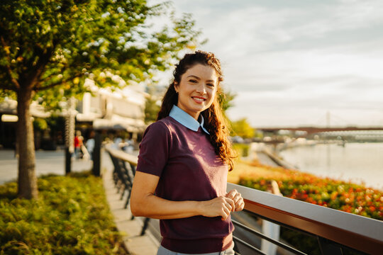 Smiling woman posing at urban waterfront during golden hour