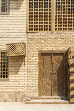 Traditional latticed windows and an ornately carved wooden door in a brick building in Khiva, Uzbekistan