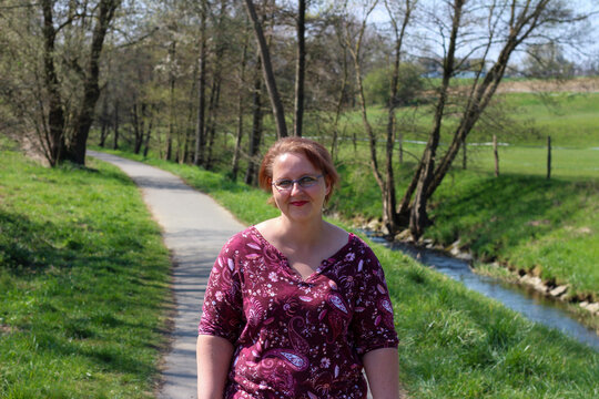 Woman with glasses smiling on path next to stream
