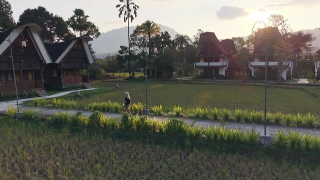 Woman walking through toraja village rice paddies at sunset in sulawesi