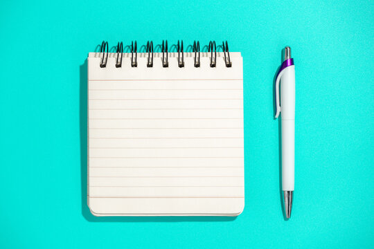 notepad and pen on blue background, top view