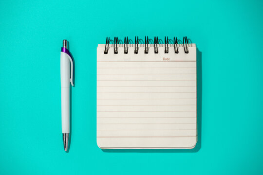 notepad and pen on blue background, top view