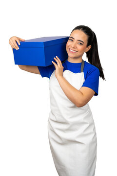 Woman in apron and blue shirt smiling while holding a blue box on her shoulder