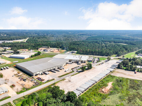Industrial warehouse and logistics center aerial view. Large distribution facility with loading docks and parked semi-truck trailers. Supply chain operations and freight transport concept