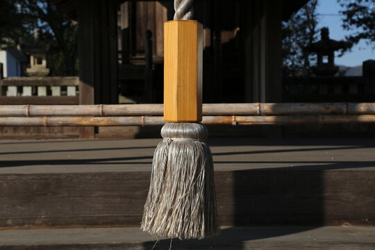 Close-up of a ceremonial bell rope at a Shinto shrine in the morning sun.