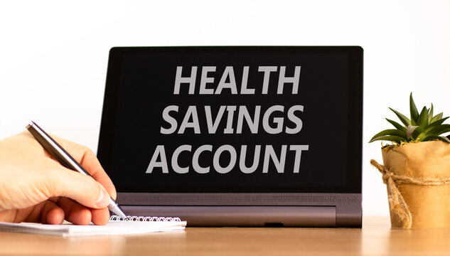Health saving account symbol. Concept words Health saving account on beautiful black tablet. Beautiful white background. Businessman hand. Medical Health saving account concept. Copy space.