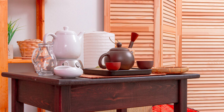 Tea set with ceramic teapots, cups and serving tray arranged on wooden table. Traditional tea ceremony and mindful daily ritual. Asian tea culture, hospitality and relaxation concept