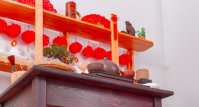 Chinese tea set displayed on wooden counter with red lantern decorations. Traditional tea ceremony and Chinese culture. Lunar New Year celebration and festive decor. Asian tea service
