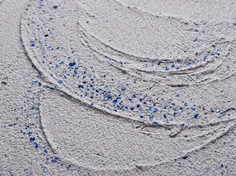 Intricate sand art design with blue glitter traces showcasing