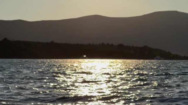 Golden Sunlight Reflection on Sea Waves with Mountain Coast Silhouette
