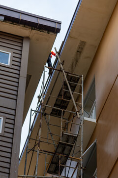 Construction Worker on Scaffolding Repairing Building Exterior