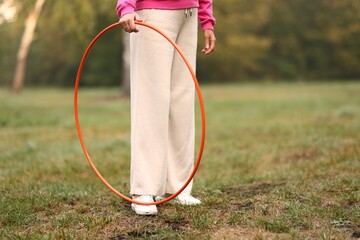 Senior woman exercising with hula hoop outdoors, closeup. Space for text © New Africa