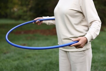 Senior woman exercising with hula hoop outdoors, closeup © New Africa