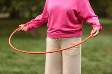Senior woman exercising with hula hoop outdoors, closeup © New Africa