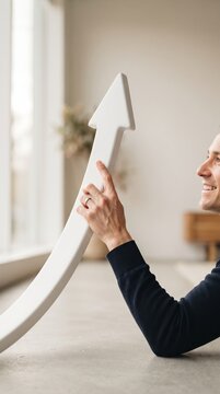 smiling businessman holding large white upward arrow on floor visualizing financial success market growth and career progression