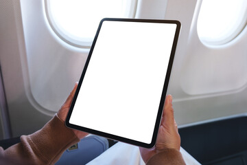 Mockup image of a woman holding digital tablet with blank desktop screen next to an airplane window © Farknot Architect