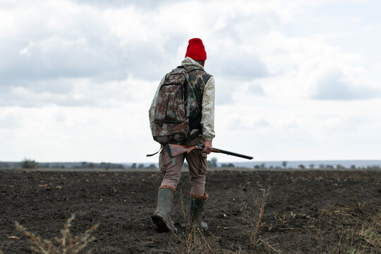 A hunter with a gun in camouflage clothing. A gentleman with a gun, medium shot, unrecognizable.