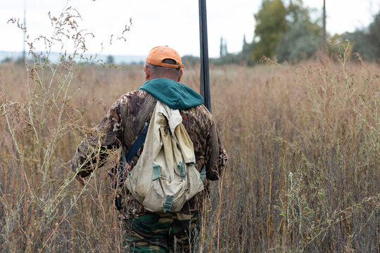 A hunter with a gun in camouflage clothing. A gentleman with a gun, medium shot, unrecognizable.