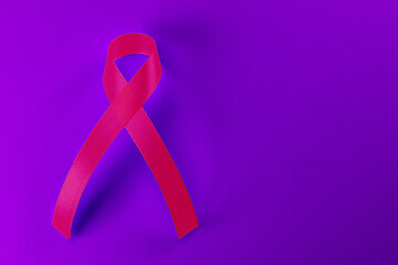 Obraz na płótnie Canvas Pink ribbon emblem for cancer support on vibrant purple background.