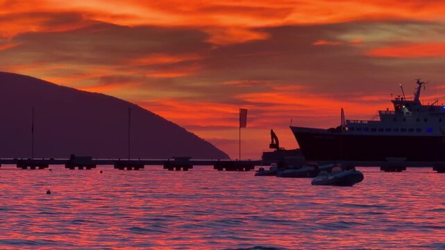 Ship Against Vibrant Orange Sunset Sky Over Calm Sea 