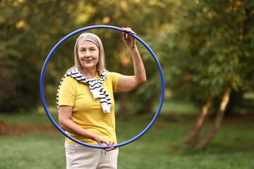Senior woman with hula hoop in park, space for text © New Africa
