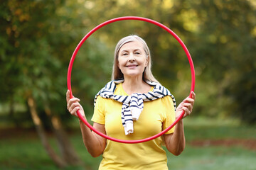 Senior woman with hula hoop in park © New Africa