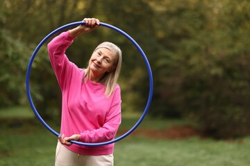 Senior woman with hula hoop in park, space for text © New Africa