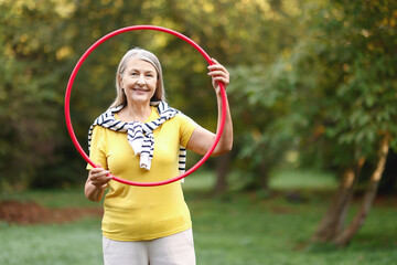 Senior woman with hula hoop in park, space for text © New Africa