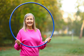 Senior woman with hula hoop in park, space for text © New Africa