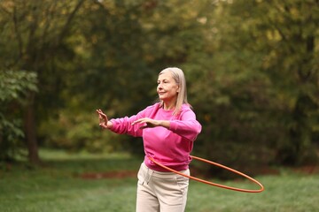Senior woman exercising with hula hoop outdoors © New Africa
