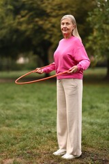 Senior woman exercising with hula hoop outdoors © New Africa