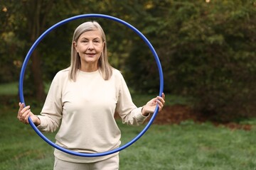 Senior woman with hula hoop in park, space for text © New Africa