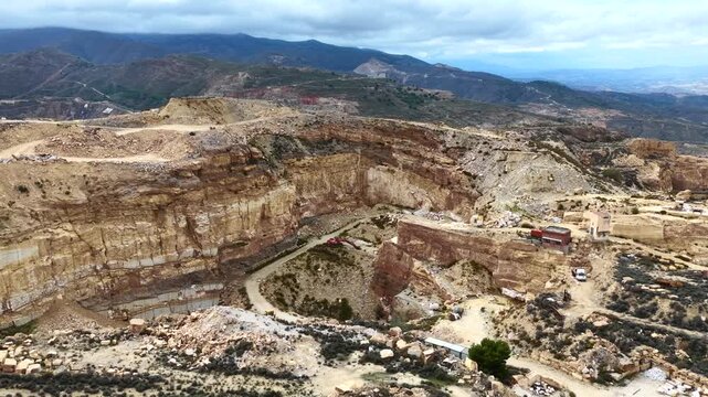 4K aerial drone b-roll flyover above massive marble quarry with terraced stone cliffs   