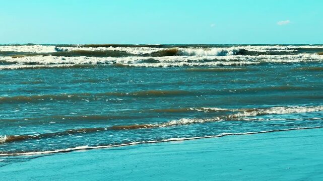Ocean Waves Rolling Onto Sandy Beach Shore Under Clear Blue Sky 