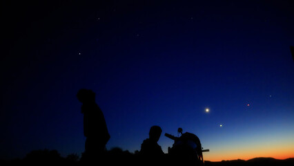 Amateur astronomers observing stars, planets, Moon and other celestial objects with a telescope in nature. © astrosystem