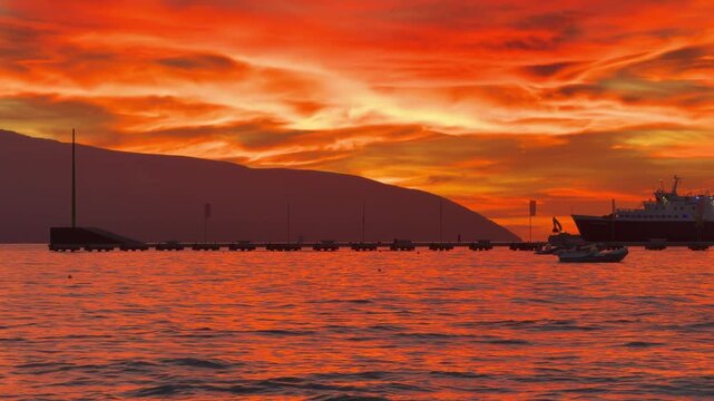 Orange Sunset Sky Over Calm Sea With Silhouettes Of Ships And Pier
