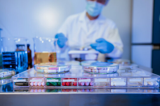 Biotechnology research laboratory desk filled with medicine samples and blurred scientist testing chemical solution scene for clinical study development project