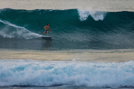 Surfer on a powerful ocean wave, carving across the water with white spray