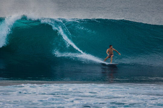 Surfer on a powerful ocean wave, carving across the water with white spray