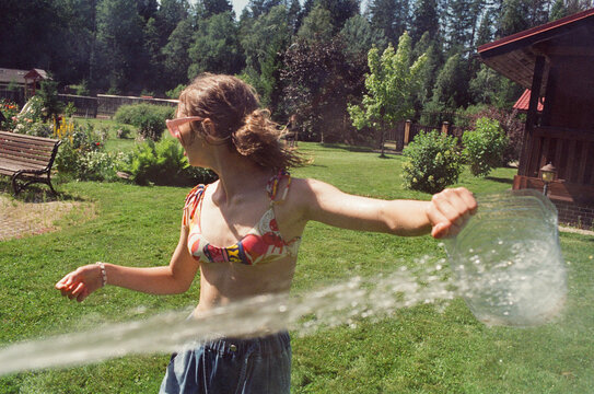 Teenage girls are splashing water on each other in the backyard