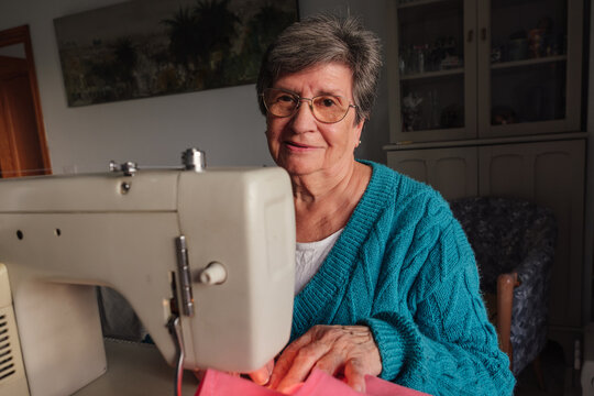 Senior woman enjoying hobby machine sewing at home