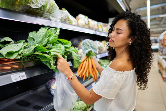 Woman shopping fresh organic vegetables in supermarket produce section