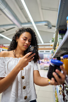 Woman scanning product barcode with smartphone in grocery store