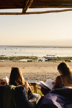 Anonymous Two friends relaxing by the beach at sunset in Indonesia