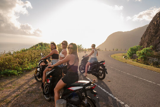 Four friends on scooters during a girls trip at sunset in Indonesia