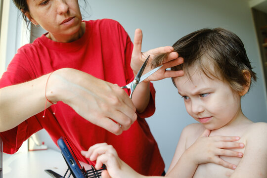 Little boy looking skeptical during a haircut by his mother.