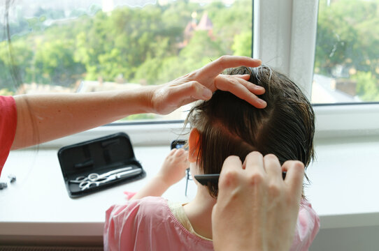 Mother sectioning her son's hair with a comb before cutting.