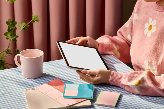 Young woman holding a tablet device while sitting at a table