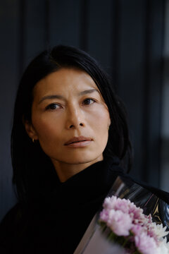Woman Holding Flowers in a Thoughtful Moment of Urban Beauty