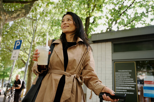 Woman Walking With a Drink in a City Street in Daytime